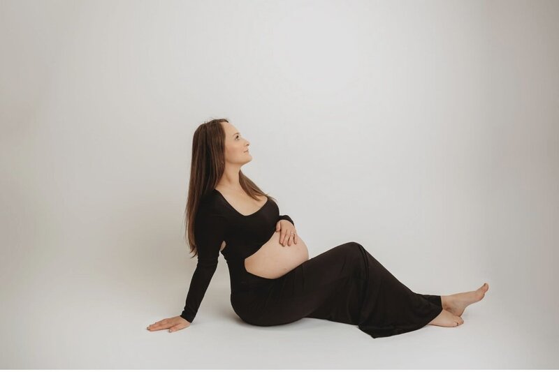 Pregant mom sitting on the floor with hand over belly.