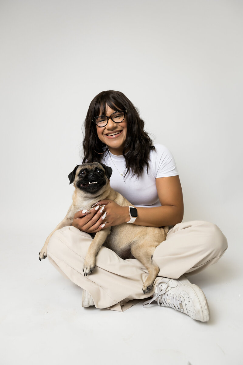 Woman and pet pug dog sit together and smile for the camera