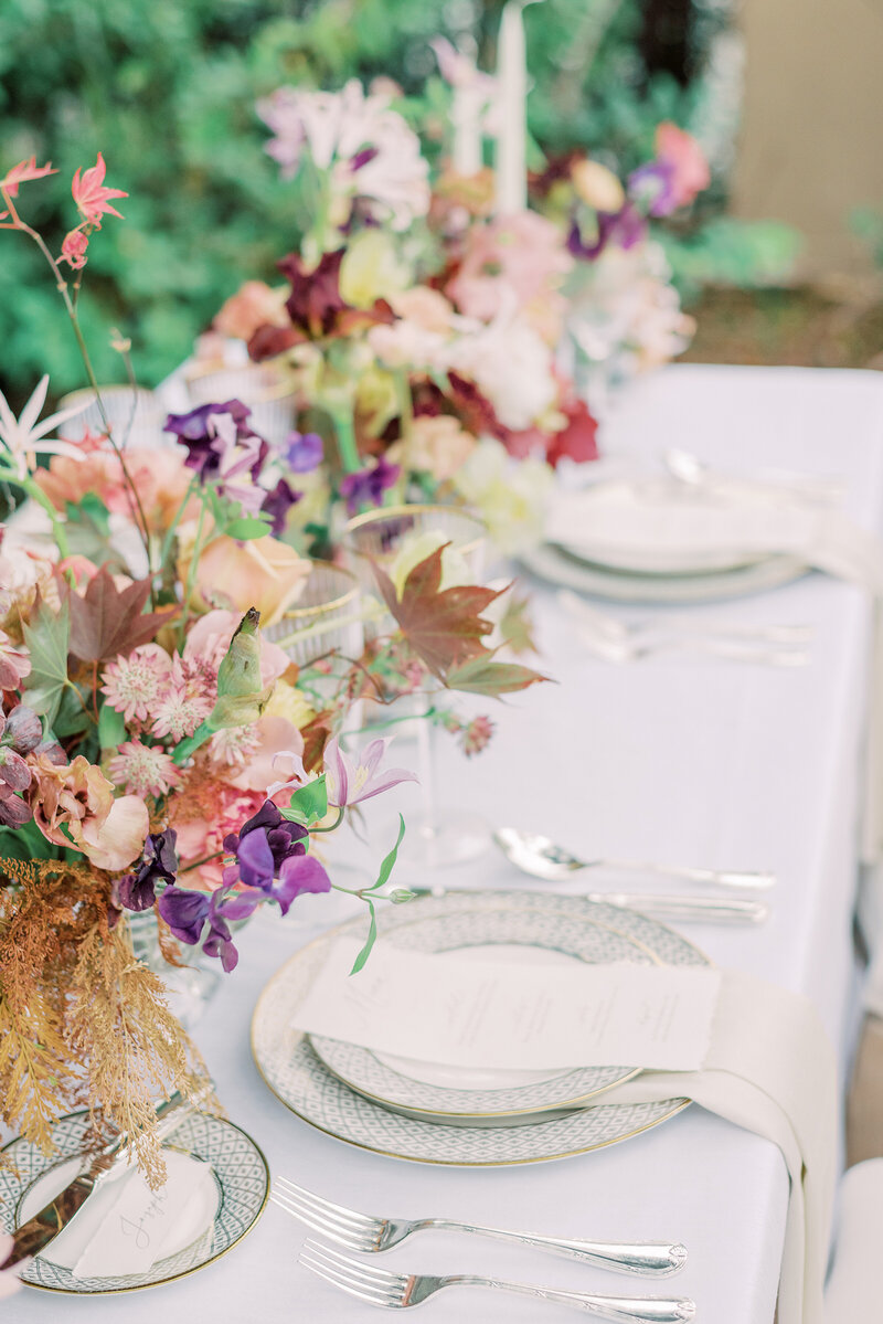 5-alisonbrynn-Radiant-LoveEvents-Maxwell-1-House-detail-table-setting-long-menu-on-gold-accent-plates-tropical-colorful-floral-centerpiece-across-table-outdoors-romantic-elegant-timeless