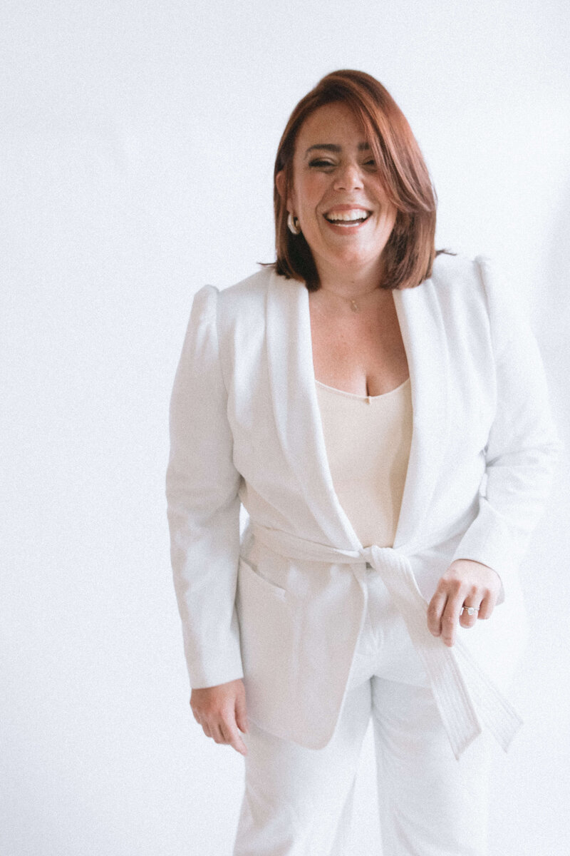 Casey, Founder of Most Valuable Bridesmaid smiling at the camera wearing white suit.
