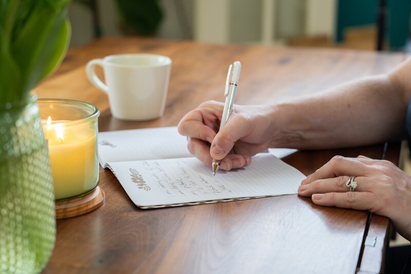 woman holding a pen and writing in a journal