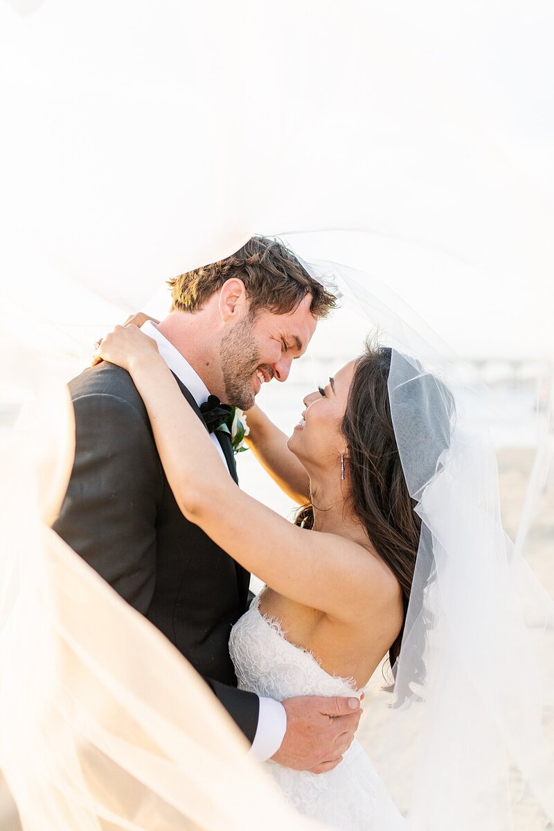 Bride and groom kissing under veil at Scripps Forum wedding venue in La Jolla, California.