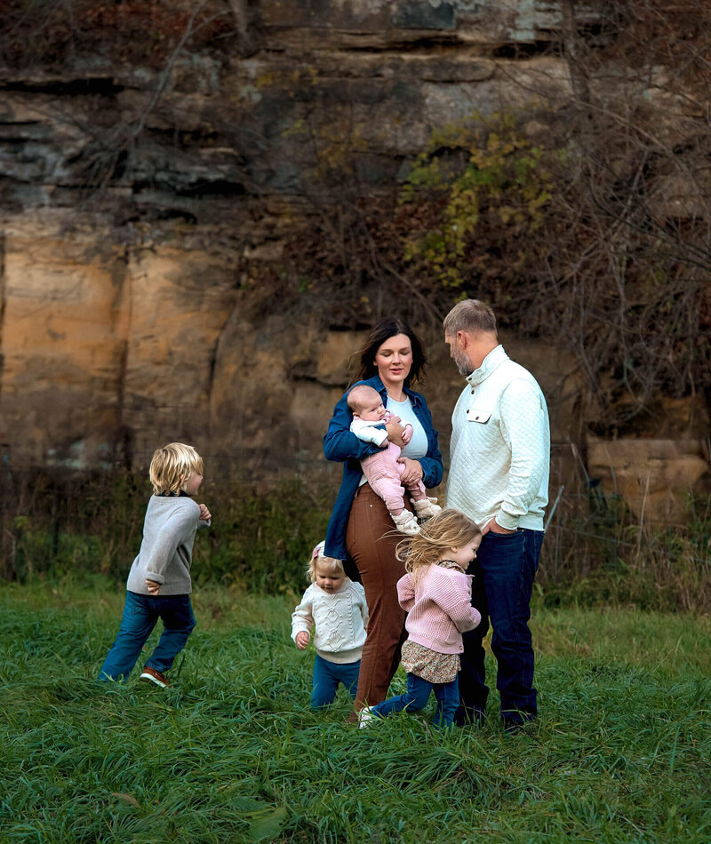 Mom and dad with baby and 3 kids running around them