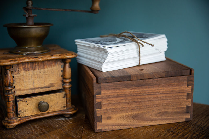 Wooden keepsake wedding box on a shelf next to antique furniture.