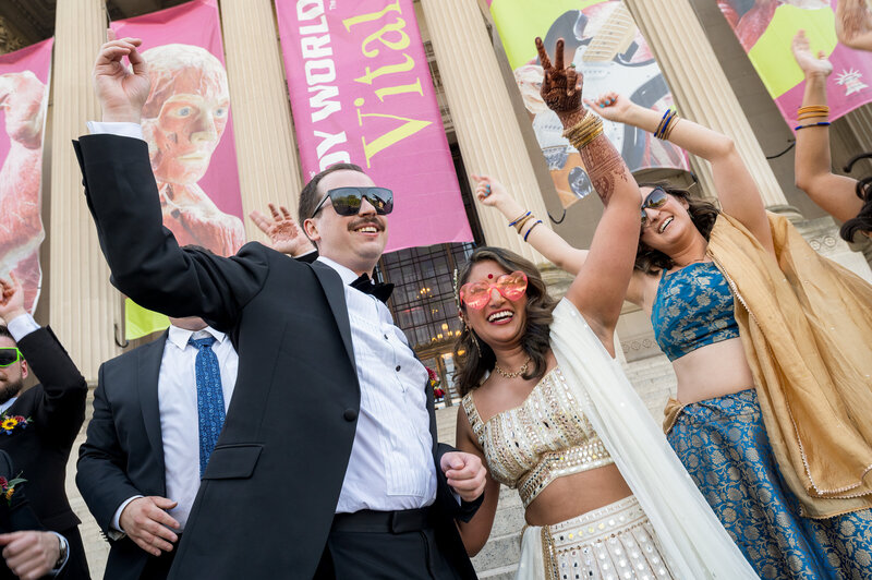 Bride and groom wearing sunglasses as they dance in front of the Franklin Institute during their Sangeet.