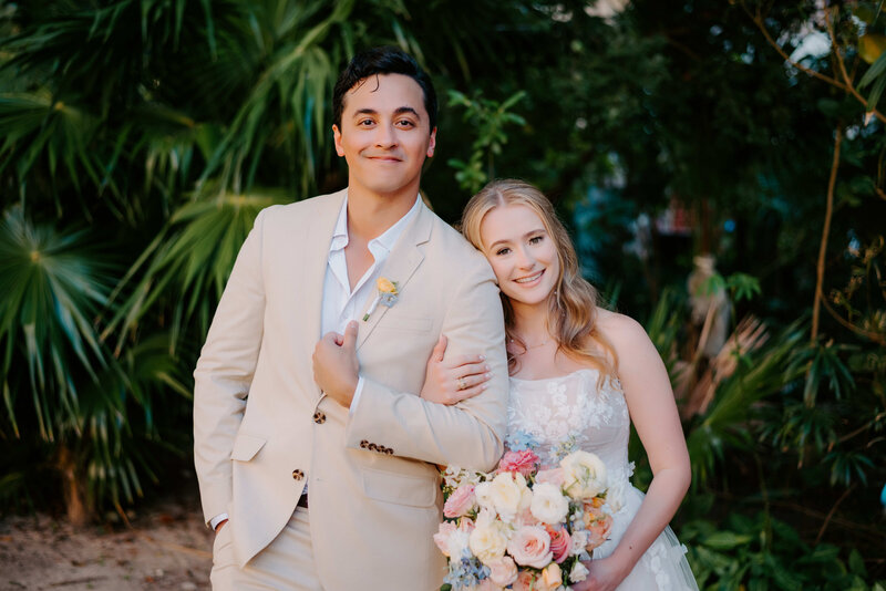 Romantic wedding portrait of a newlywed couple standing outdoors in a lush tropical garden