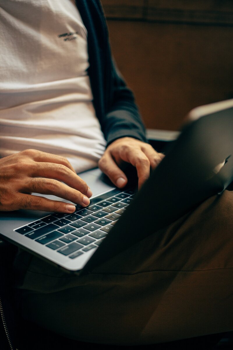 a man's hands write on his laptop on his lap