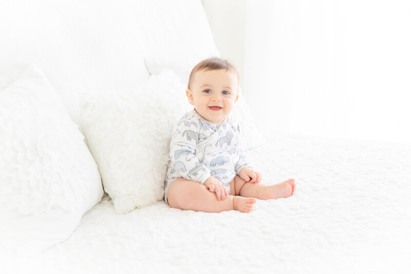 Baby boy sitter on a  white bed