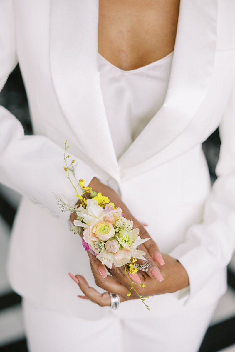 Bride in white suite with flowers on wrist