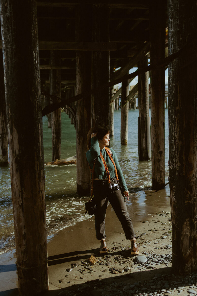 Alaska photographer posing under a pier for her branding photos