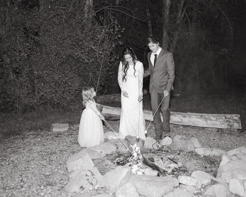 Couple making smores with their daughter after the wedding.