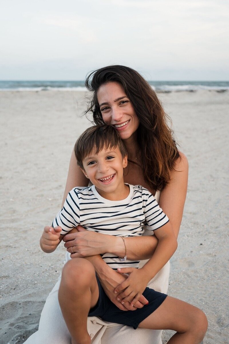 Son and mom warmly smiling at the camera during a photoshoot at a Charleston beach