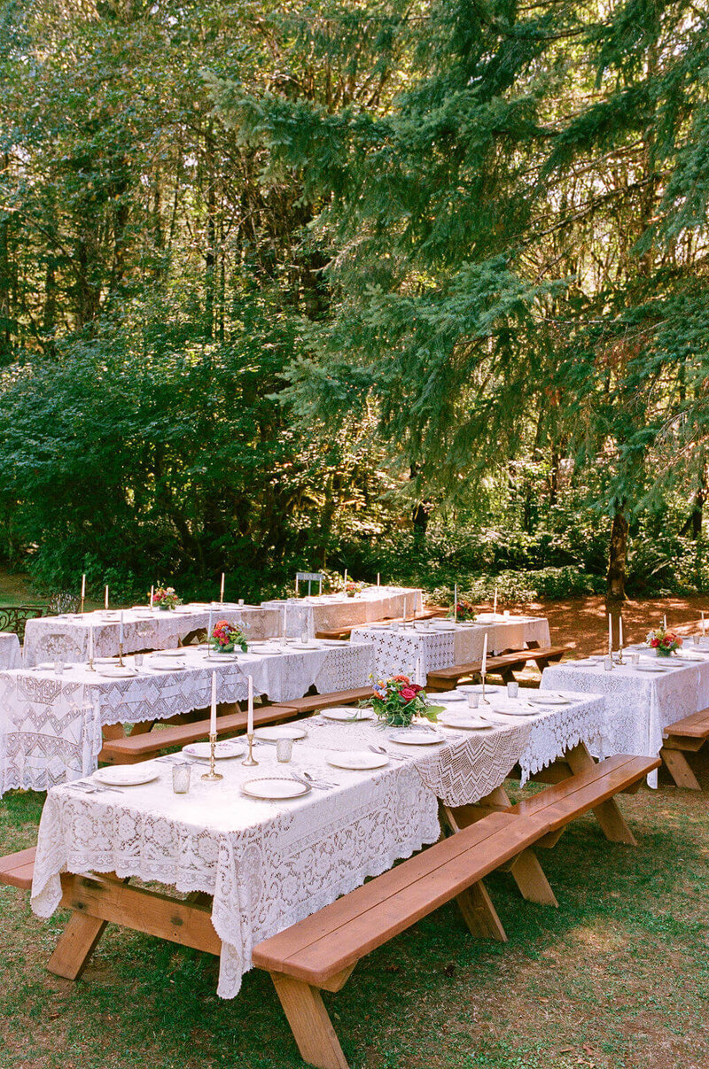 Tablesettings with candles, china, and lace tablecloths at a wedding planned by Eugene wedding planners Birdie June Events and Rentals.