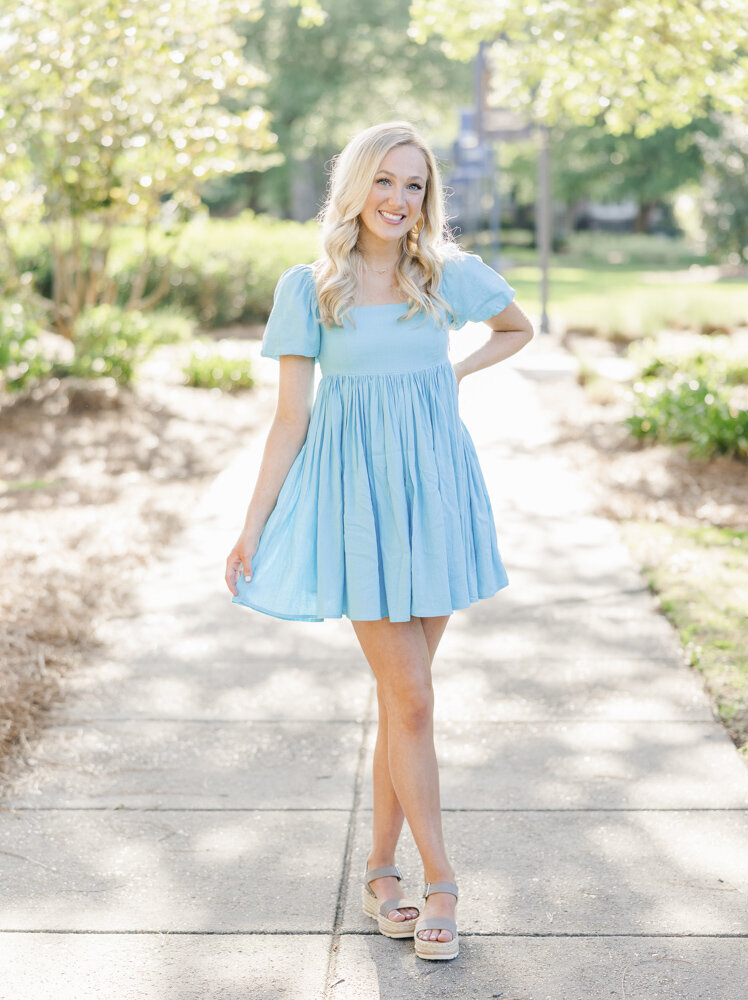 girl in a blue dress standing with her legs crossed