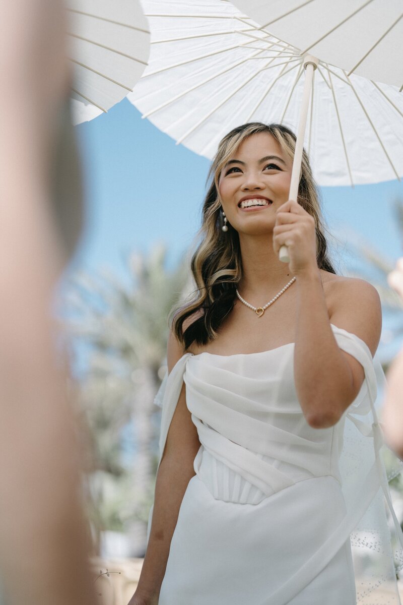 Bride with parasol in elegant wedding dress at Hotel del Coronado, designed by Thater Made, a luxury wedding and event producer in San Diego, CA.