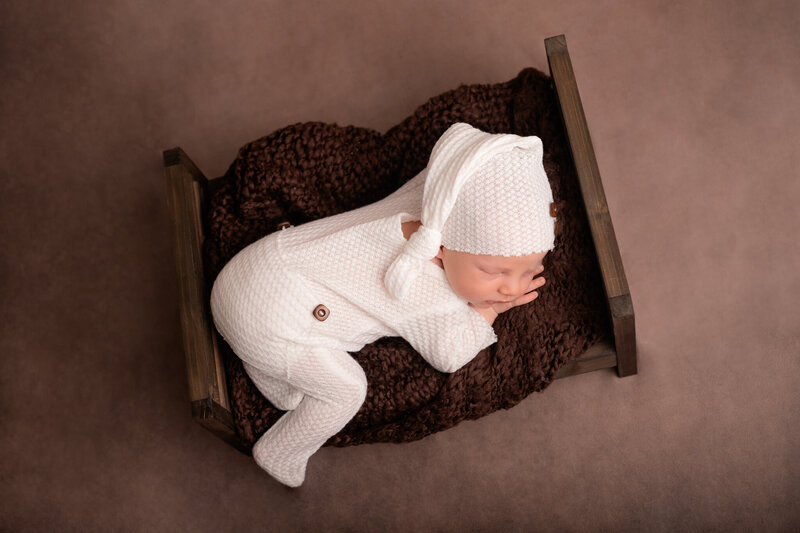 nyfödd bebis ligger med pyjamas i en liten säng