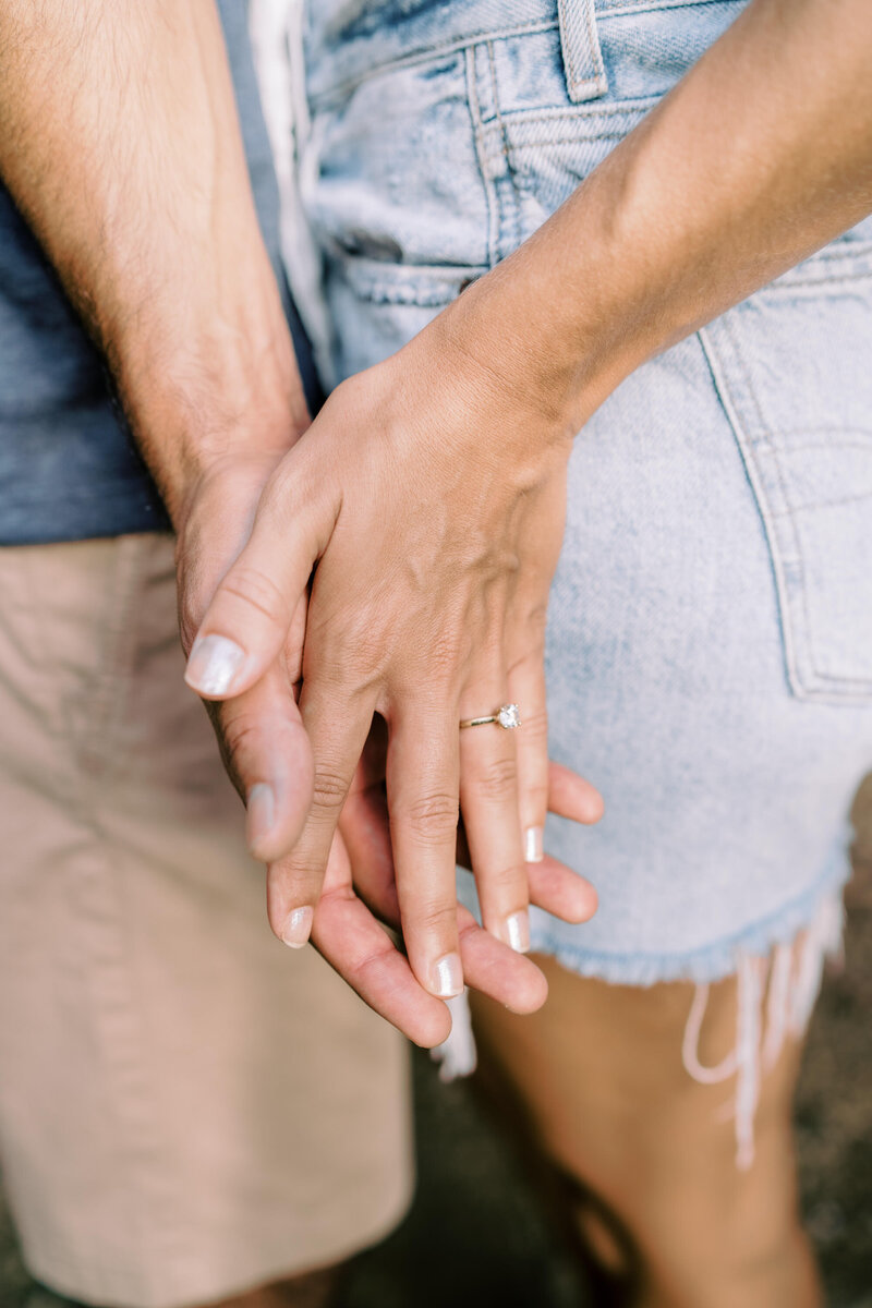 close up photo of newly engaged couple holding hands. Photography by Megan Moura