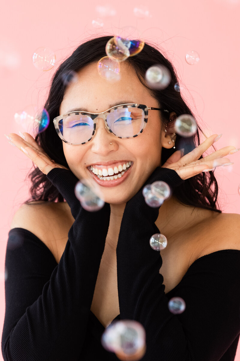 Portrait of Anh Nguyen laughing behind bubbles.