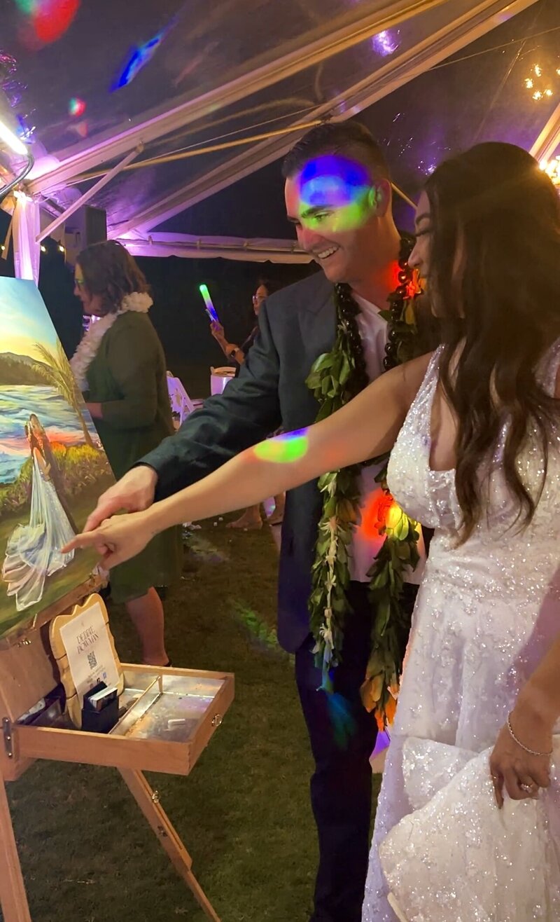 Justin and his wife smiling and pointing out details on their live wedding painting