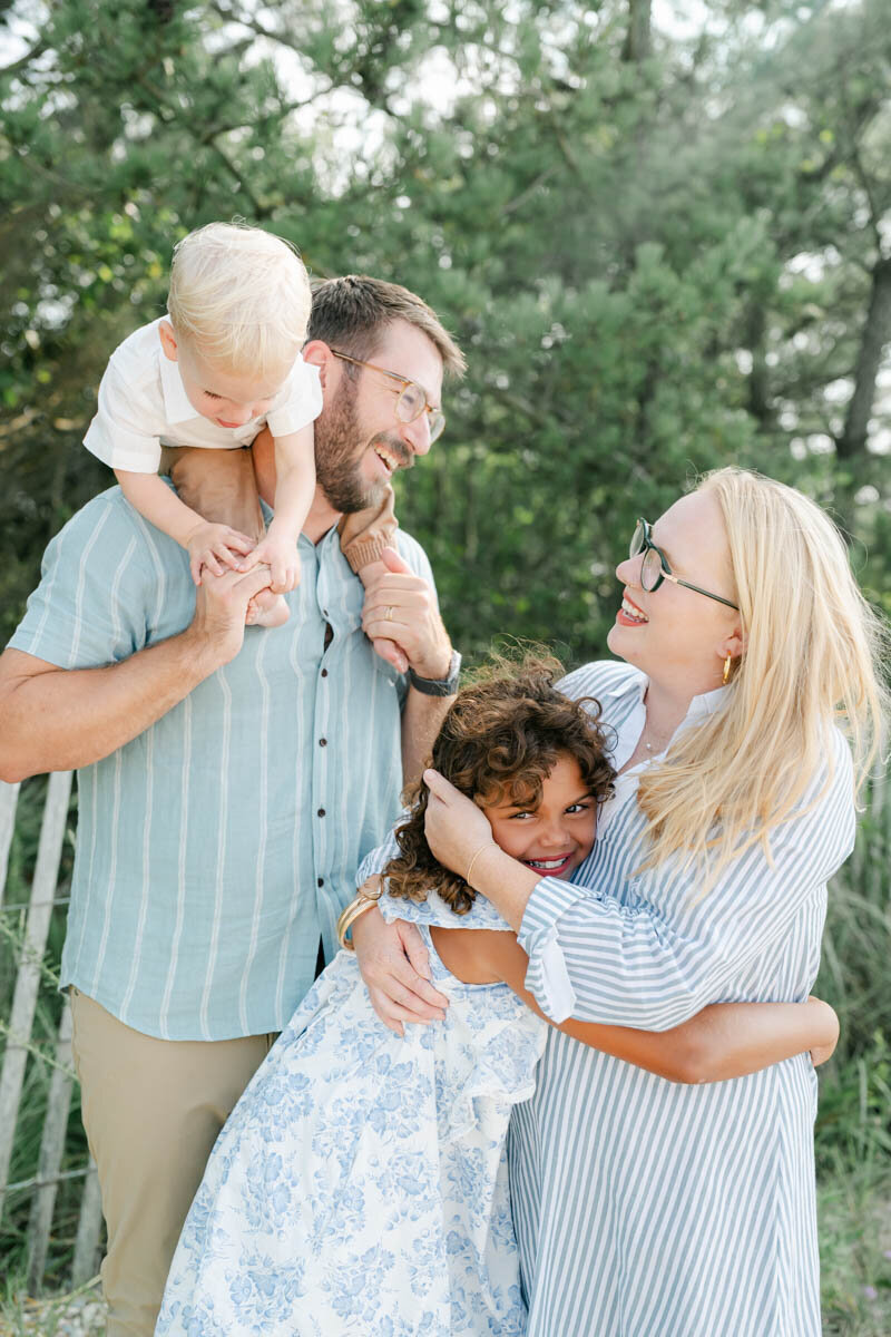 mother kneels to laugh with son in suspenders