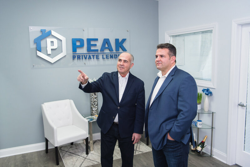 The owner of Peak Private Lending talking and pointing to the whiteboard with his partner.
