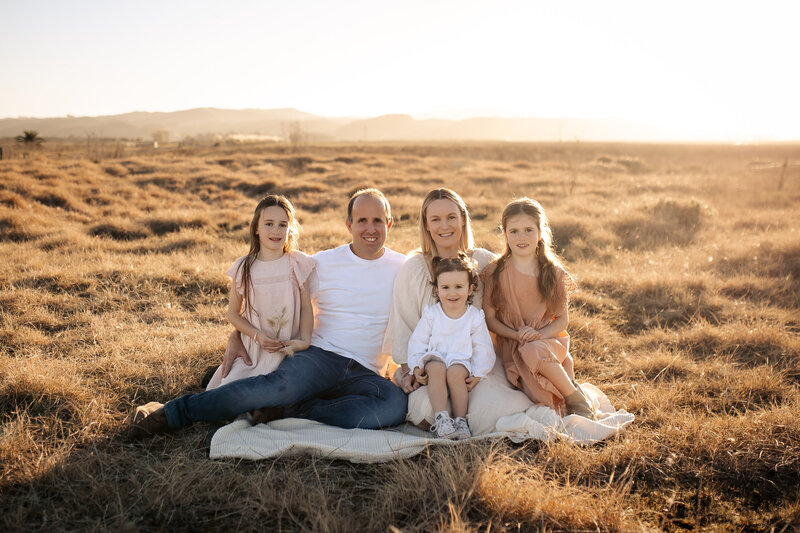 Family of four enjoying a playful moment on Waipatiki Beach, Hawke’s Bay – joyful family photography by a local Hawke’s Bay photographer, capturing cherished memories along the stunning coastline near Napier and Hastings