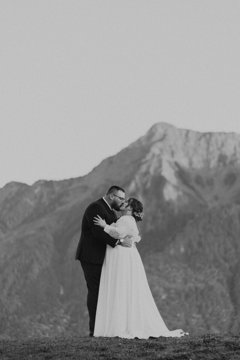A black and white photo of a couple kissing in front of Mt. Cheam at the Fraser River Lodge