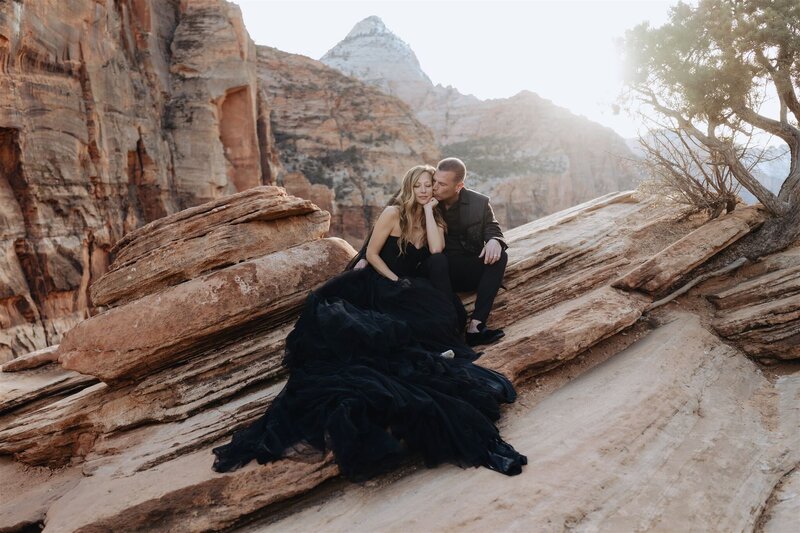 Couple cuddling while sitting on the beautiful red rocks in zion