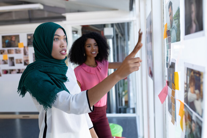 Two Black women, including a woman wearing hijab, have a strategic planning session.