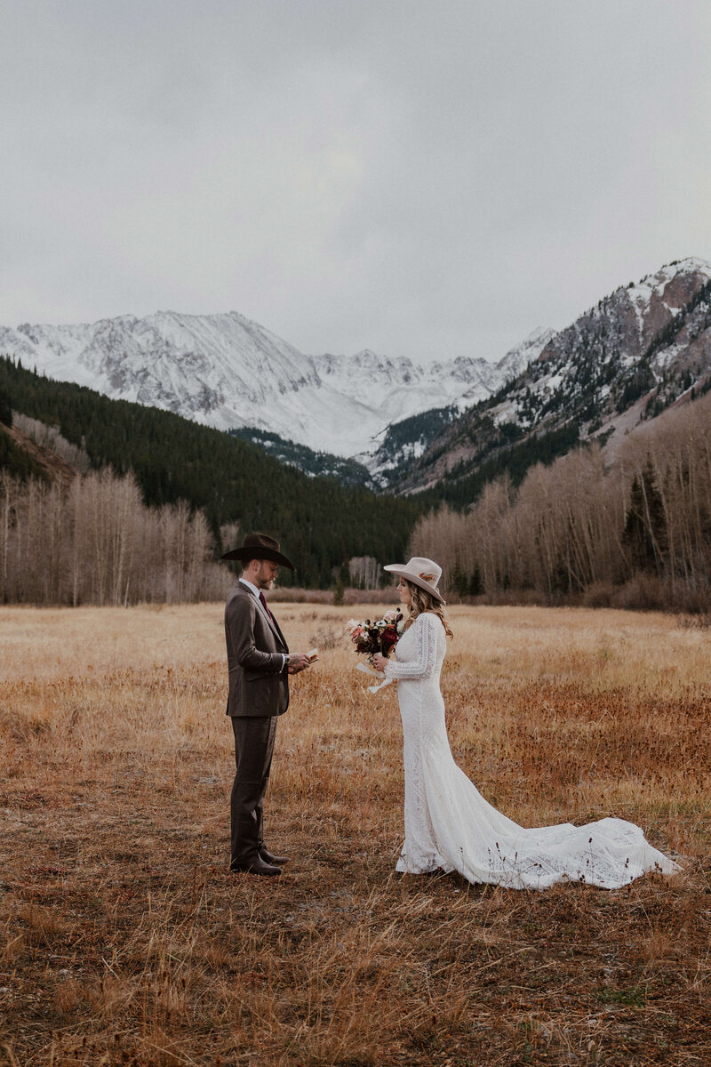 couple stands at the bottom of trees with the 10 mile range behind them
