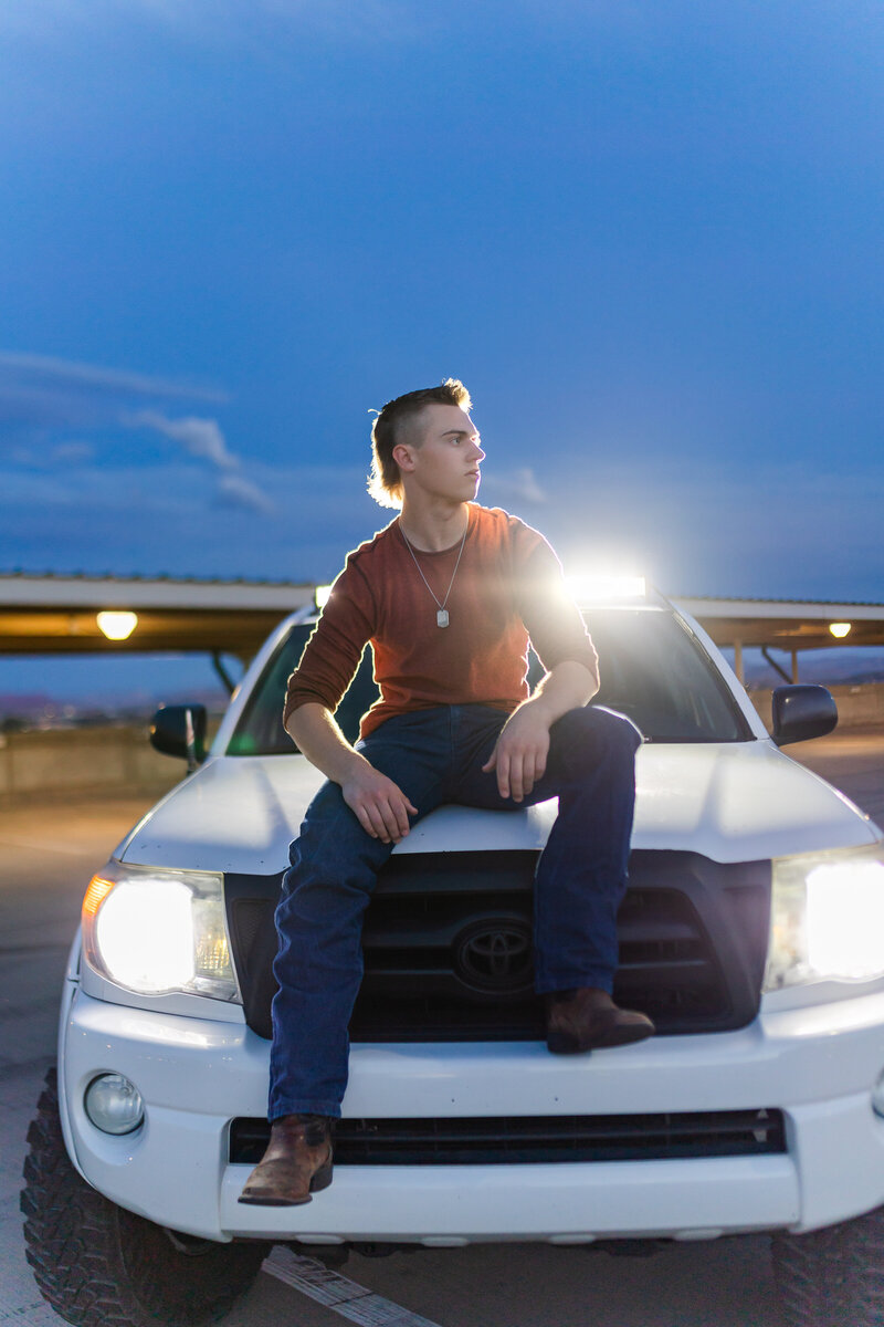boy sitting on the hood of his truck and posing for senior photos in st george utah