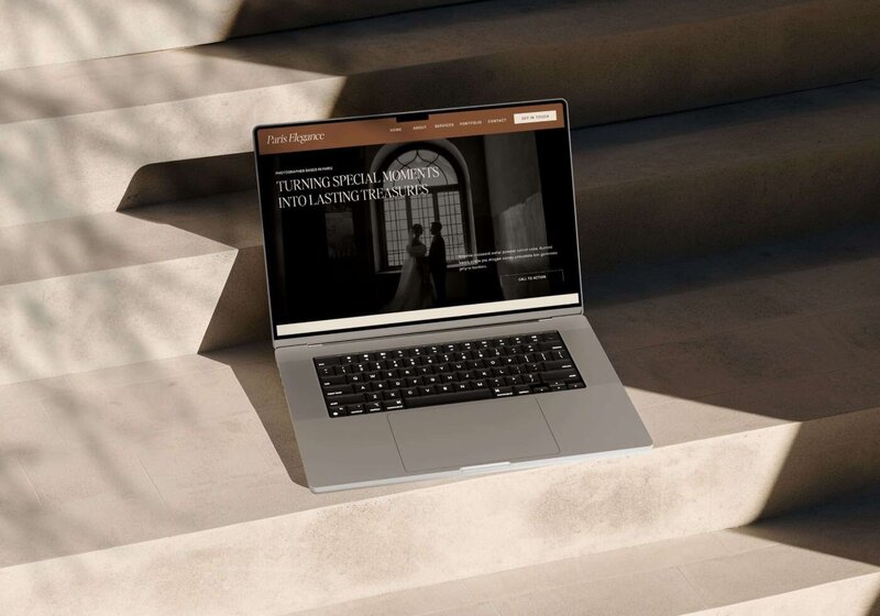 Laptop placed on sunlit stone steps, screen showing the “Paris Elegance” wedding photography website homepage with a black-and-white photo of a bride and groom standing in front of tall windows.