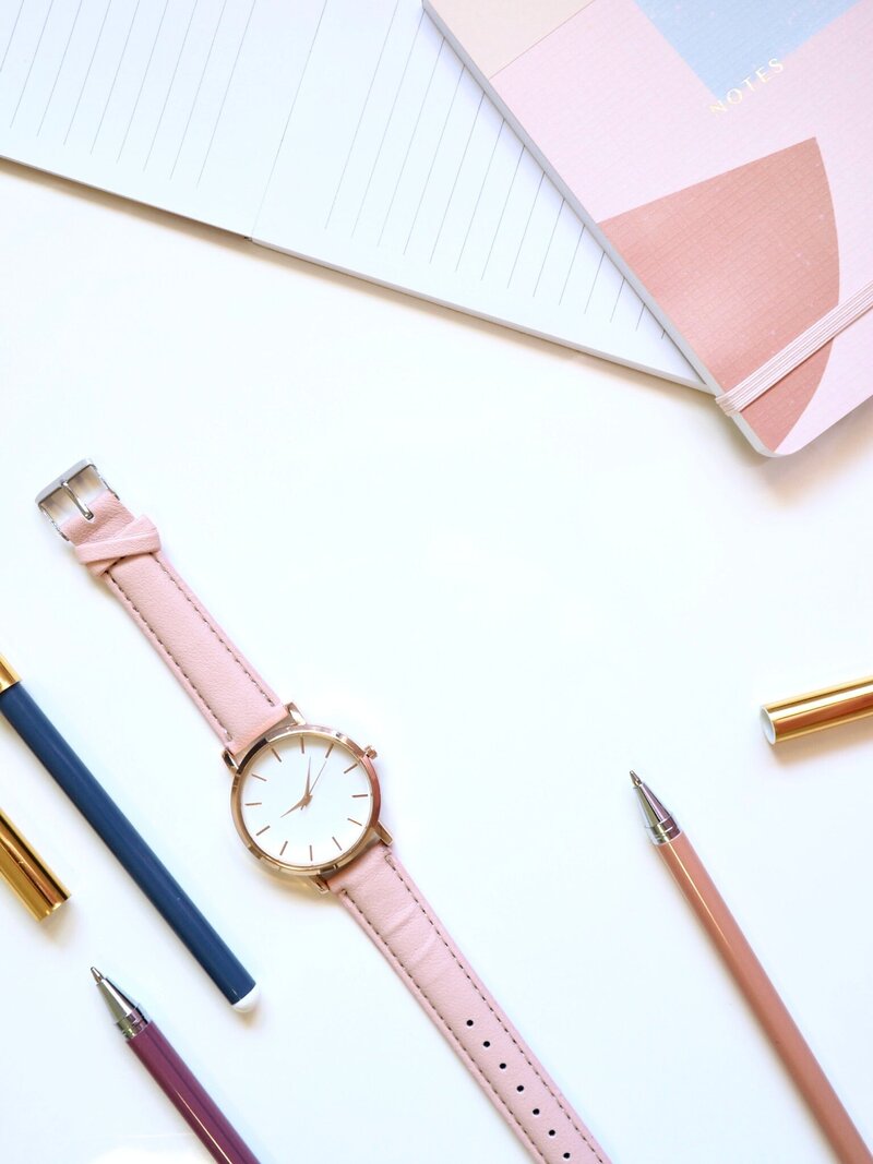 Pens, paper, and a watch on a white background
