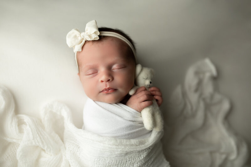 newborn baby girl posing with her parents during her newborn session