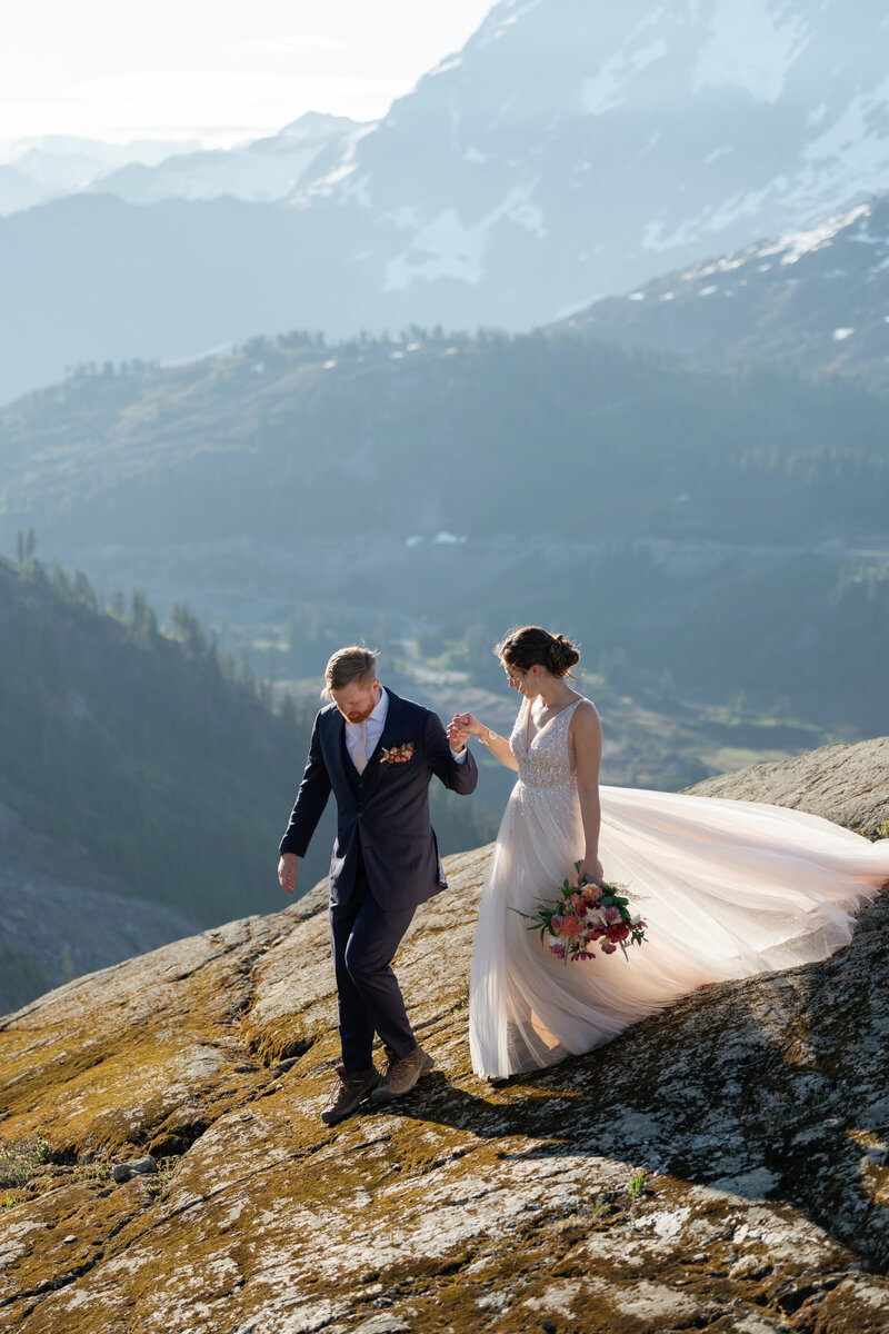 Bride and groom walking down a mountain in Oregon after their elopement, with the bride wearing a tulle gown