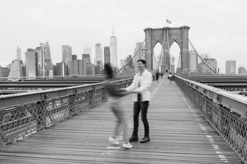 couple holds hands on brooklyn bridge