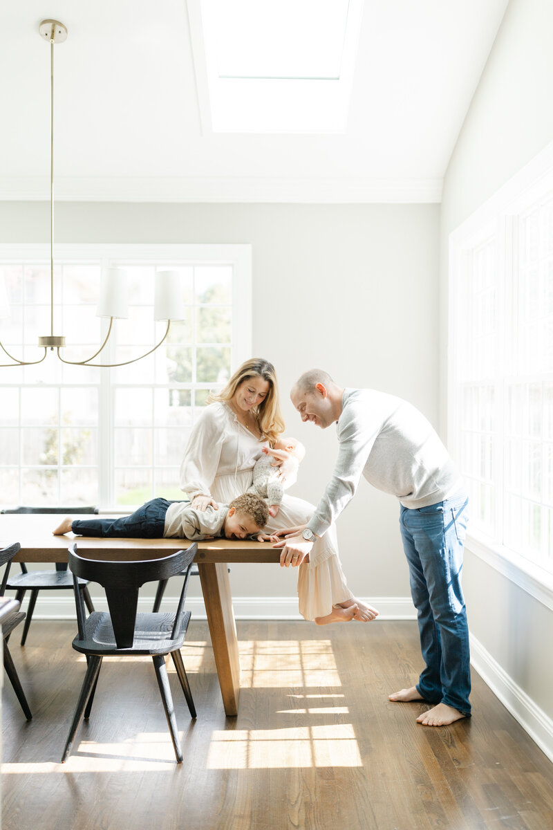 New parents take newborn portraits at home with their young son
