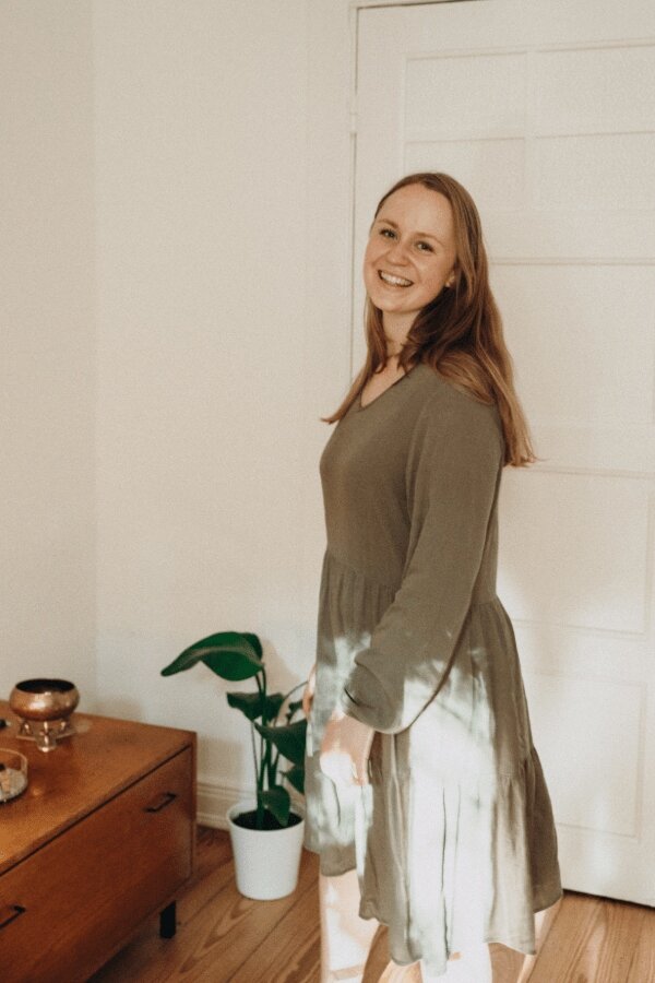 Eine junge Frau in einem  dunkelgrünen Kleid lächelt in die Kamera