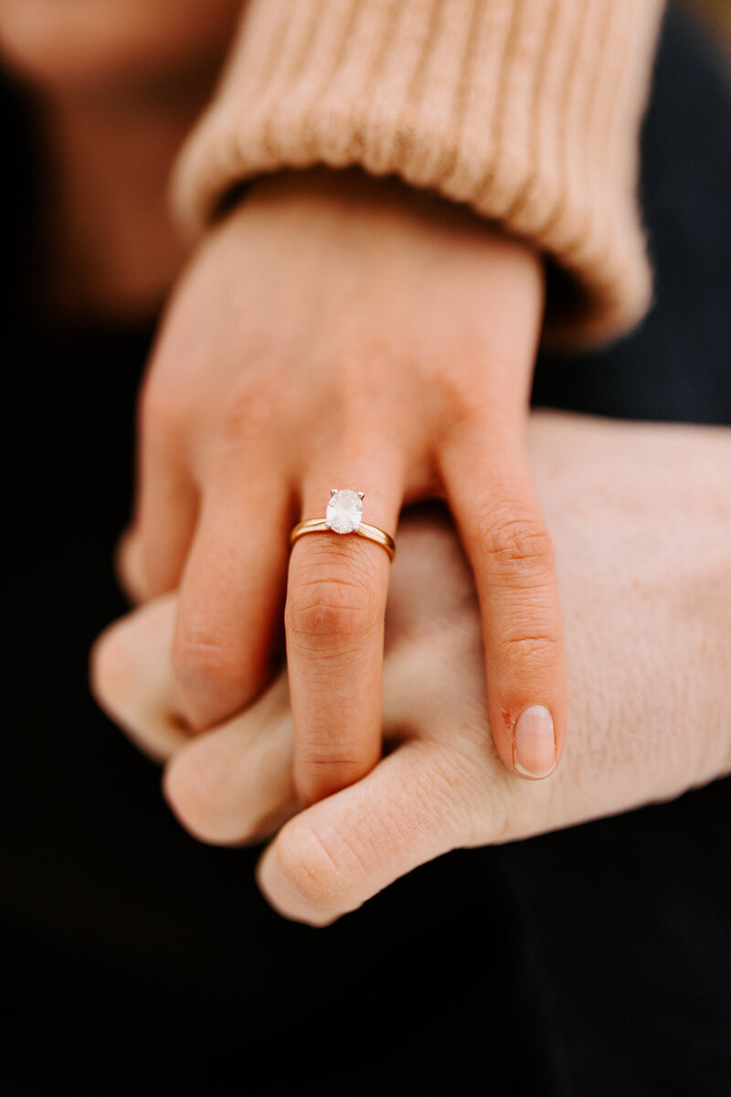couple holding hands with large engagement ring