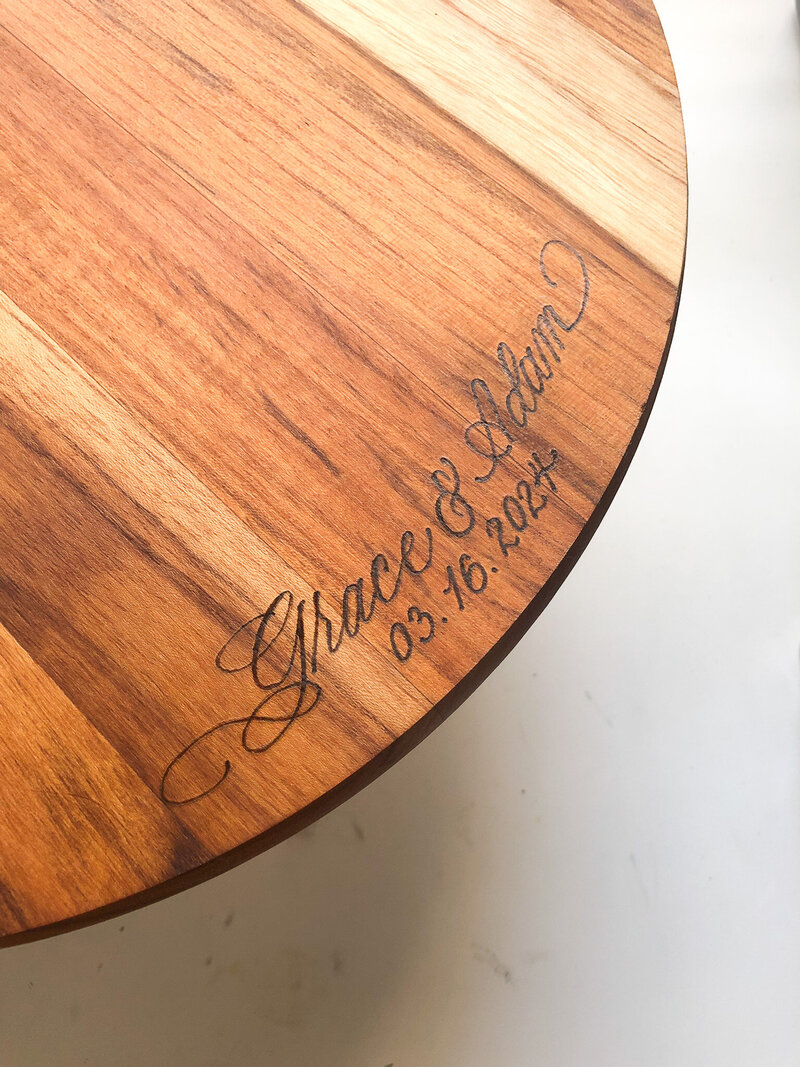 Closeup image of a chestnut colored wooden cake stand with calligraphy wood burning