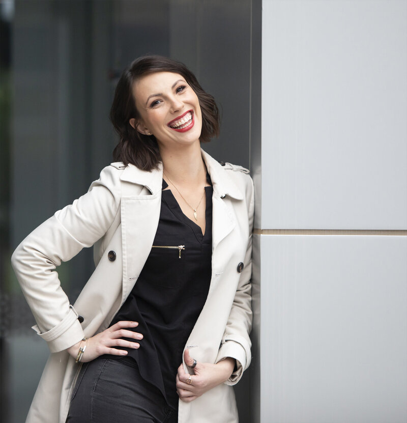 business lady in trench coat leaning against wall