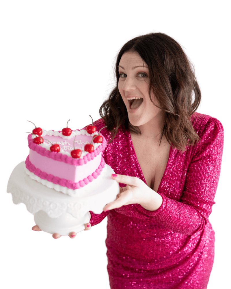 Emily in a pink dress holds a heart-decorated cake, reflecting her vibrant personality as a web designer.