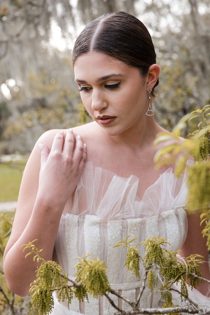 editorial close-up portrait of bride surrounded by foliage and the tulle of her wedding dress.
