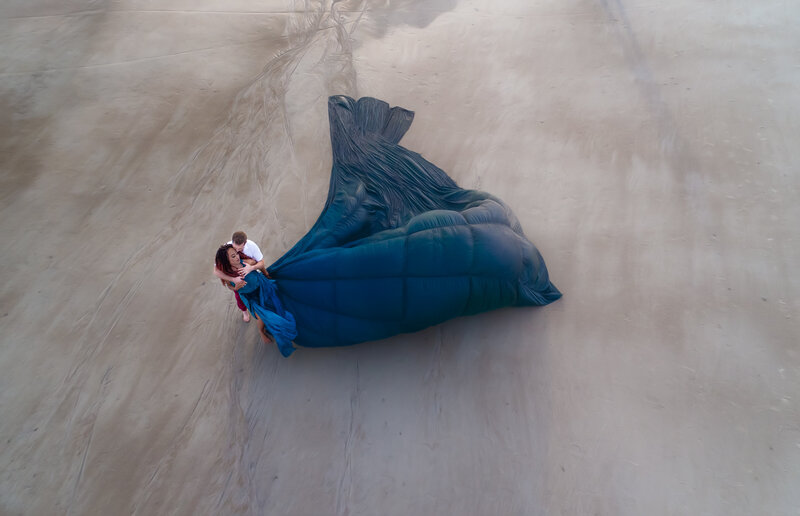 Savannah Georgia Boudoir and Glamour Woman in blue parachute gown on beach him holding her drone picture