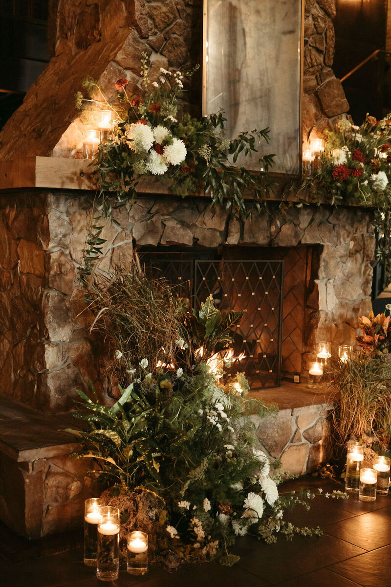 Romantic same-sex wedding with custom vows and moody floral fireplace ceremony backdrop