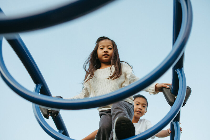  a girl and boy playing in a park caught in a playful moment climbing 
