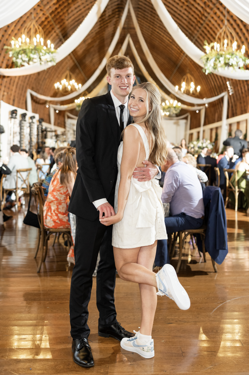 Spring wedding at WinMock at Kinderton, designed by Charming Carolina — bride in her short party dress and custom sneakers celebrating with the groom during the reception.