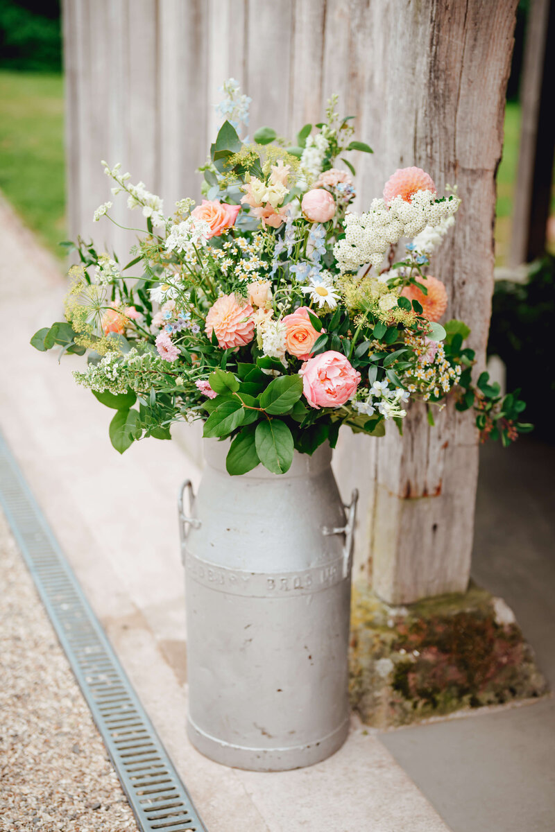 Milk churn of bright flowers at Haybarn Dulus