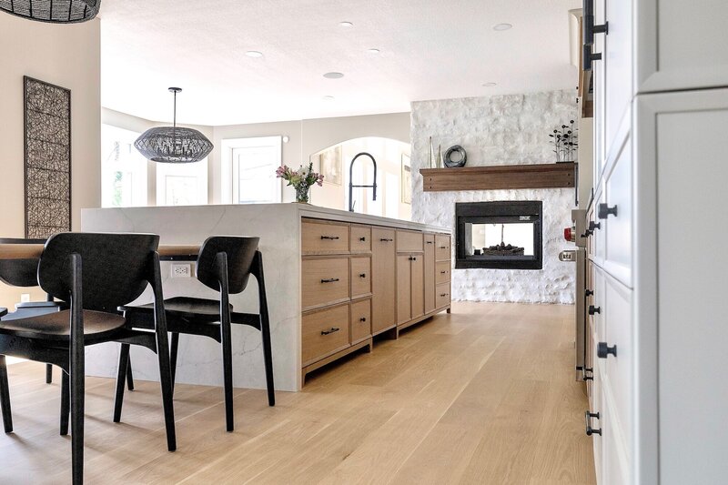 A mix of white and light wood cabinets with sleek black fixtures and white counter tops.