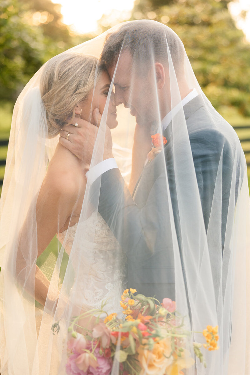 Bride and groom under bride's veil at warm, vibrant middle TN wedding